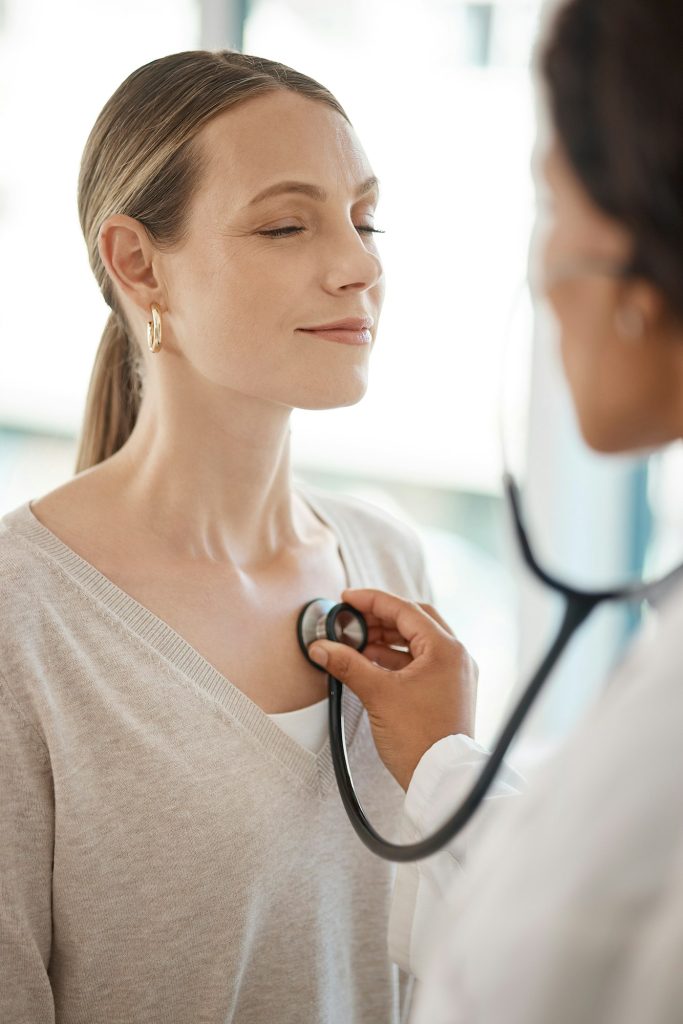 Checking and hearing heart rate with a working doctor consulting the wellness and health of a woman